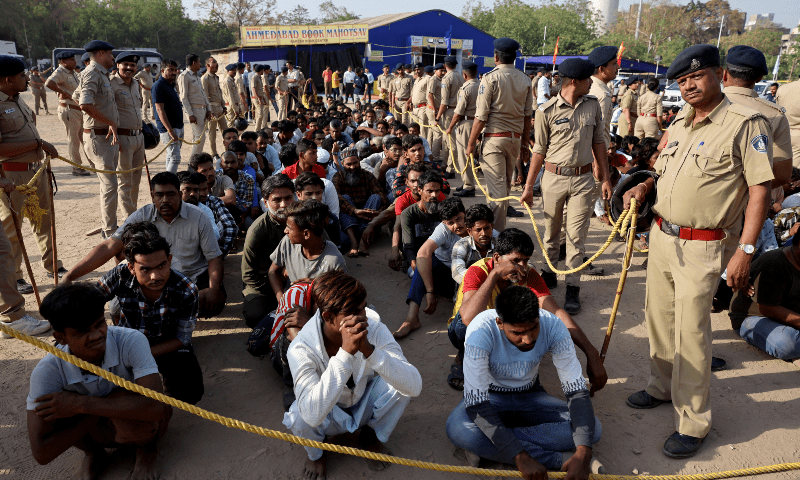 Police officers stand next to men they believe to be undocumented Bangladeshi nationals after they were detained during raids in Ahmedabad, India on April 26, 2025.&mdash;Reuters