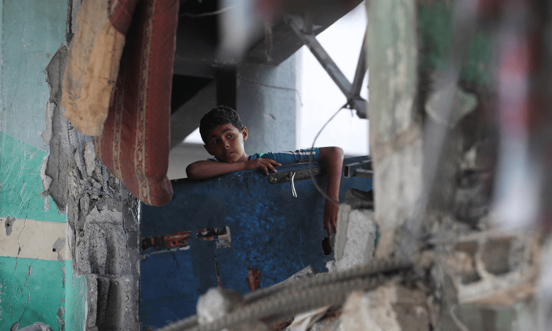 A Palestinian child looks on from a damaged building at an UNRWA school sheltering displaced people that was hit in an Israeli air strike on Sunday, in Gaza City on June 30, 2025. &mdash; Reuters