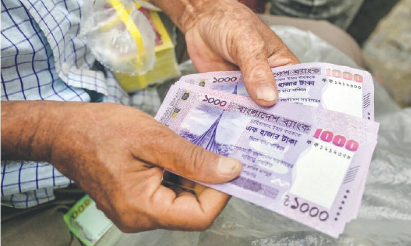 Dhaka: A man counts newly released 1,000 taka notes at a currency exchange shop on Monday. Bangla&shy;desh has issued new notes to replace designs featuring its founding president Sheikh Mujibur Rahman.&mdash;AFP