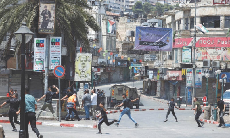 Palestinian youths hurl rocks at Israeli military vehicles conducting a raid in the old quarter of Nablus, a town in occupied West Bank, on Tuesday.&mdash;AFP