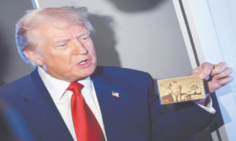 US President Donald Trump holds up the $5 million Gold Card during a chat with reporters on board Air Force One.&mdash;AFP/file