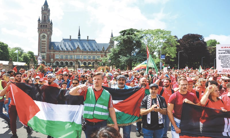 DEMONSTRATORS wearing red shirts and carrying Palestinian flags protest against Israel’s atrocities in Gaza, in front of the Peace Palace in The Hague.—Reuters