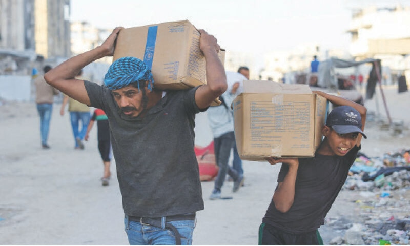 PALESTINIANS carry aid packages after trucks loaded with relief goods reportedly entered Gaza through the Israeli-controlled Zikim Gate.—AFP