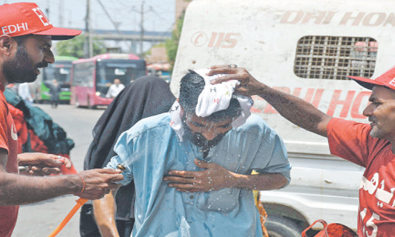 Volunteers spray water and cover the head of a passer-by with a wet towel.—Online