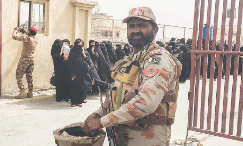 A FRONTIER Corps officer stands guard as pilgrims evacuated from Iran cross the border in Taftan.—AFP
