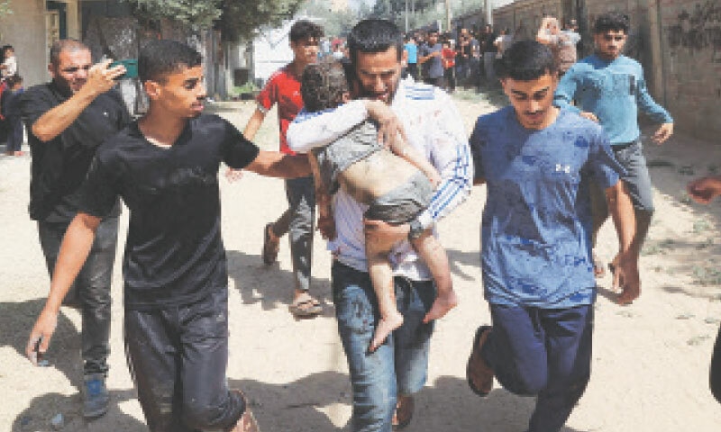 MEN rush a child, wounded by an Israeli strike on the Al-Bureij camp, to a hospital.—AFP
