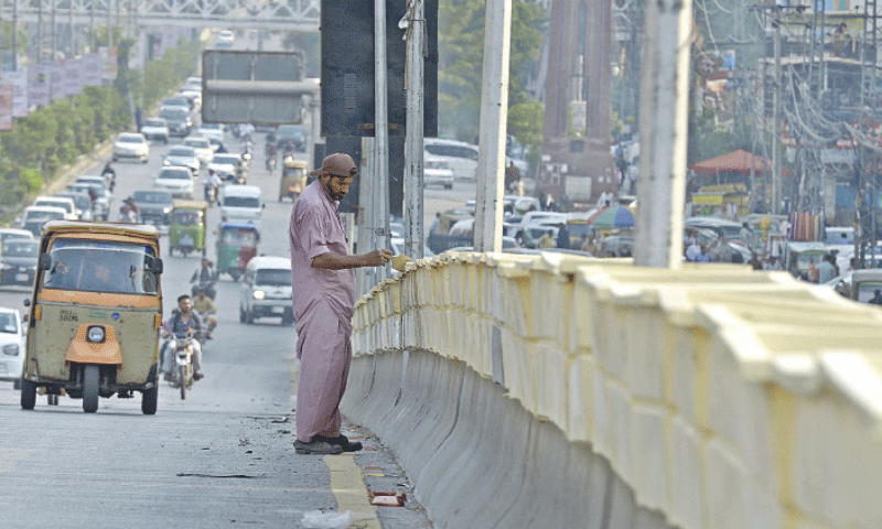 A worker paints flower pots at 6th Road Flyover in Rawalpindi on Thursday as part of beautification drive. &mdash; White Star