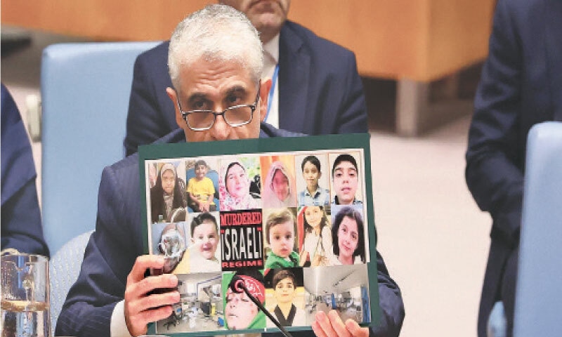 IRAN’s envoy to the UN, Amir Saeid Iravani, holds up photos of people killed in Israeli attacks as he speaks during a UN Security Council emergency meeting on threats to international peace.—AFP