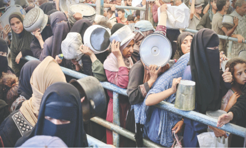 Palestinians queue in front of a hot meal distribution kitchen in Rafah on Sunday.—AFP
