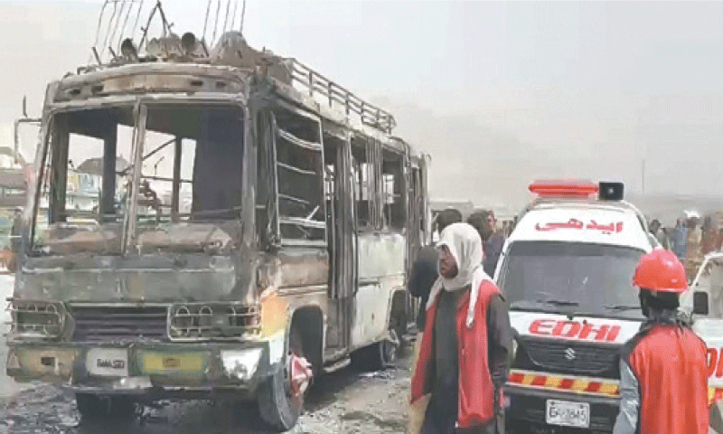 RESCUE workers stand near the bus, which caught fire after colliding with a rickshaw near Quetta’s Western Bypass.—PPI