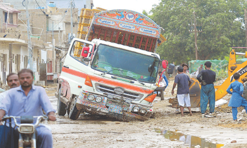 A truck is stuck in a pothole on a dilapidated road in the Malir Halt area after rain.— PPI A truck is stuck in a pothole on a dilapidated road in the Malir Halt area after rain.— PPI