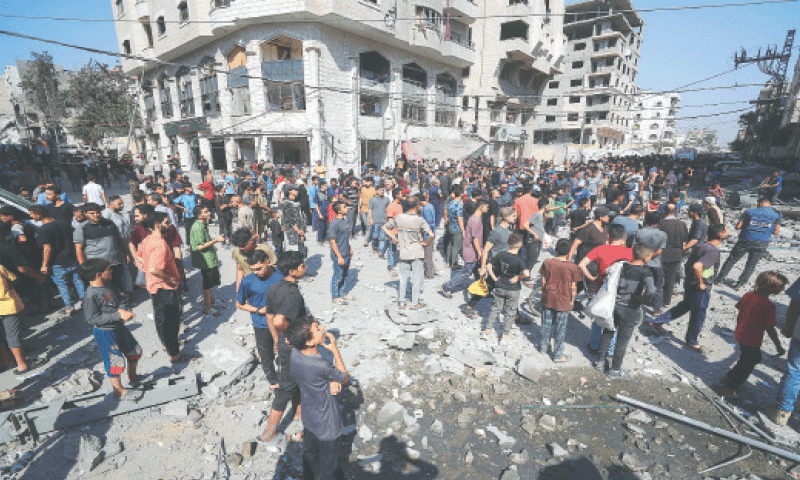 GAZA: A large number of Palestinians inspect the site of an Israeli air strike on a house.&mdash;Reuters