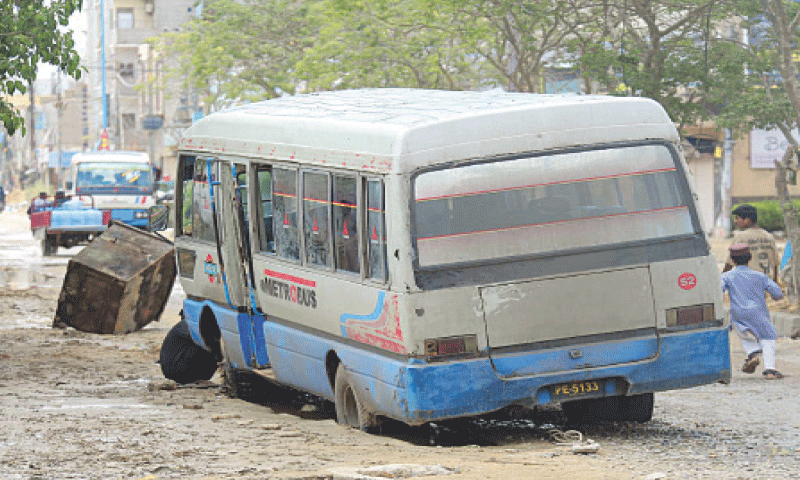 A coaster is stuck in one of the many potholes on a road in Model Colony.&mdash;PPI