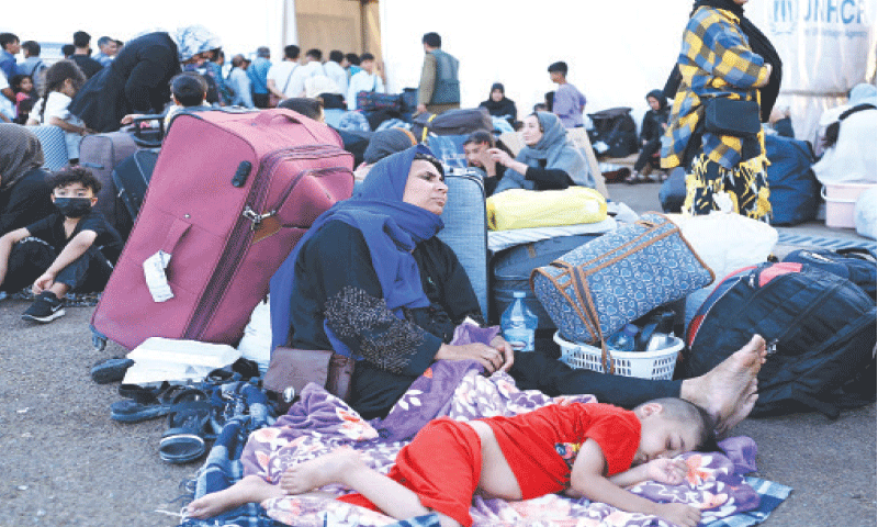 Afghan refugees rest with their belongings after arriving at the zero point of the Islam Qala border crossing between Afghanistan and Iran following their deportation.&mdash;AFP