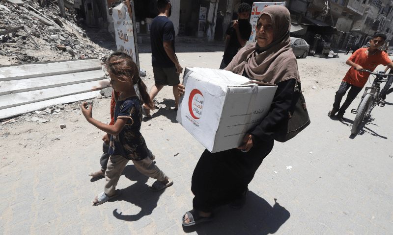  Iman Suleiman, a displaced Palestinian woman from Beit Lahiya, carries a box of aid she received from the Emirates Red Crescent, in Gaza City on June 26, 2025. &mdash; Reuters/Khamis Al-Rifi 