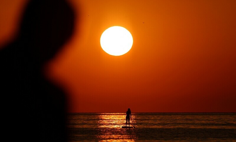 A man looks at a woman paddleboarding during a heatwave at the sunrise on the Mediterranean Sea, in Barcelona, Spain, July 2. — Reuters A man looks at a woman paddleboarding during a heatwave at the sunrise on the Mediterranean Sea, in Barcelona, Spain, July 2. — Reuters