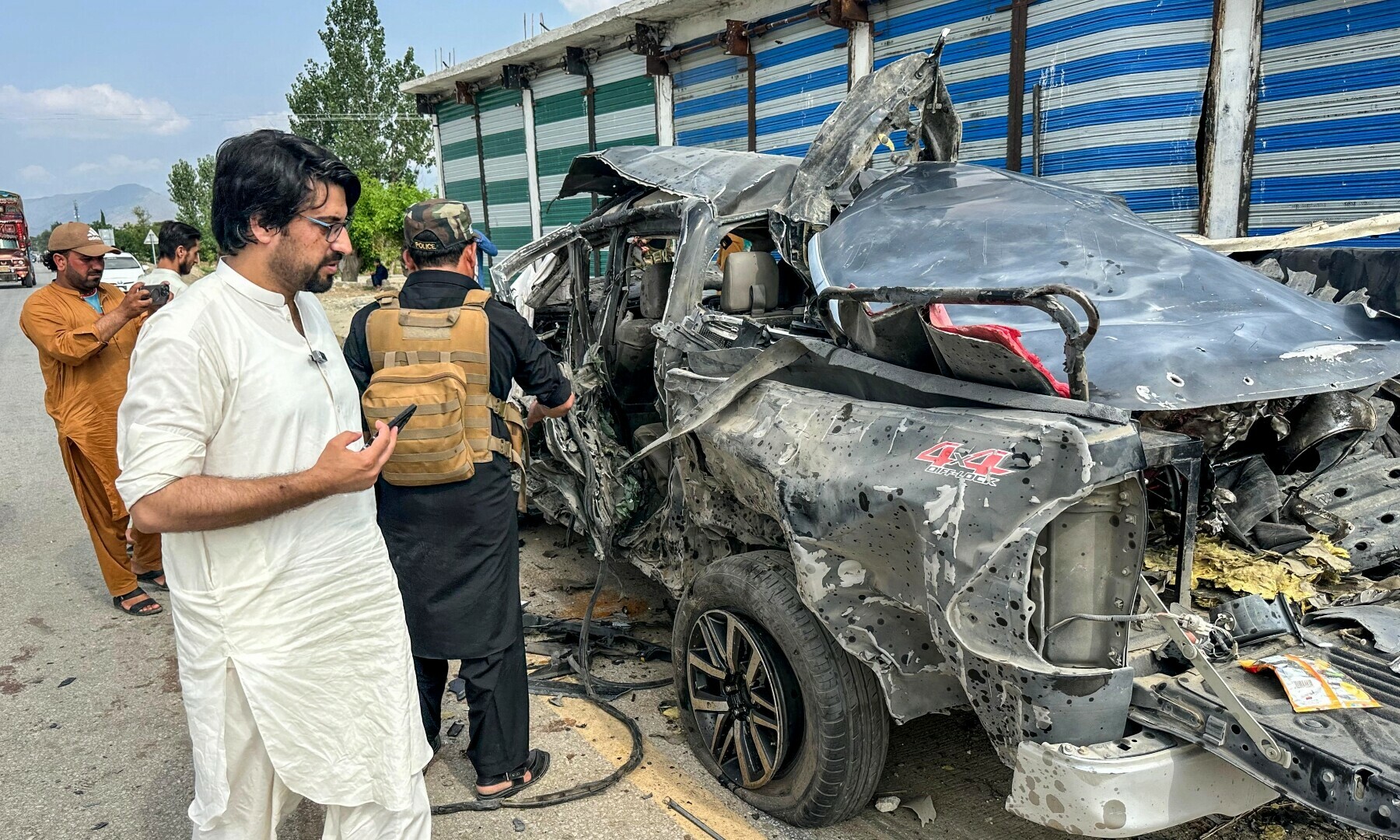 BAJAUR: Onlookers examine the wreckage of a government vehicle after it was struck by an IED blast.—AFP