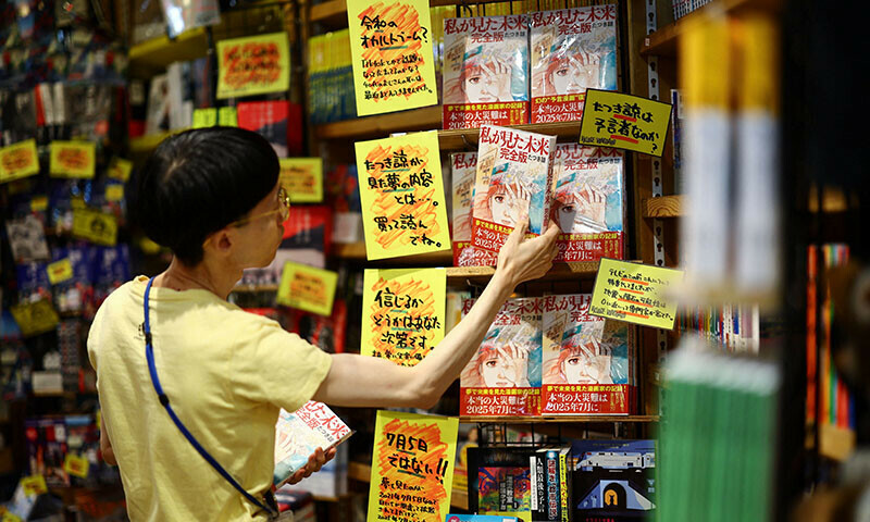 A member of staff places the comic book titled The Future I Saw, authored by artist Ryo Tatsuki, on a shelf at the Village Vanguard book store in Tokyo, Japan on June 30. &mdash; Reuters