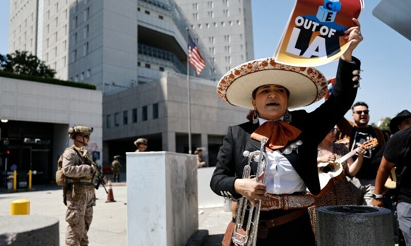 Mariachi musician Maricela Martinez holds a poster which says ‘ICE out of LA’ as she marches past US Marines standing guard on June 20, in Los Angeles, California. — AFP/File