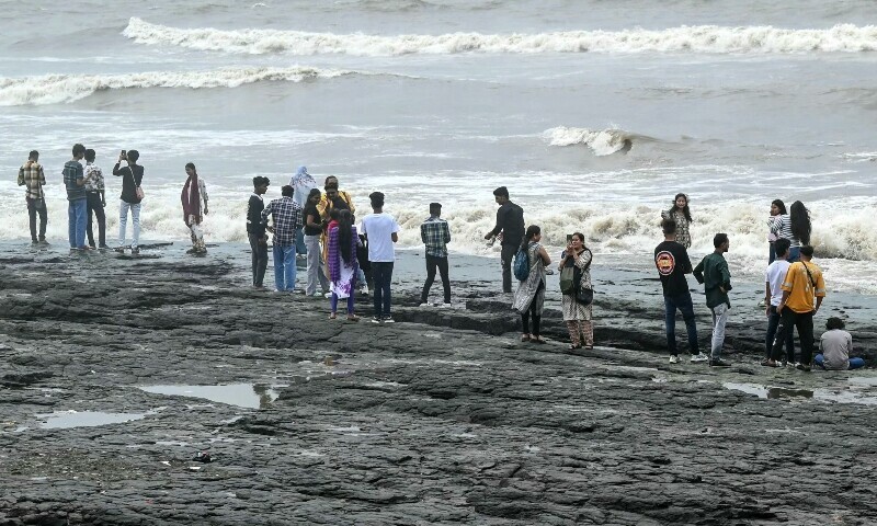 Tourists gather on a rocky shoreline as waves crash into the shore at a promenade off the Arabian Sea coast, in Mumbai, India, July 4. — AFP