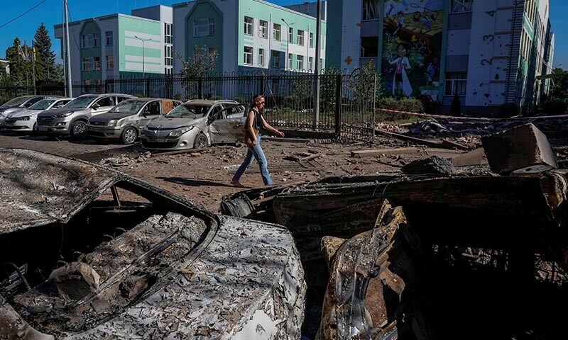 A woman passes by destroyed vehicles outside a damaged school, which was hit during Russian drone and missile strikes in Kyiv, Ukraine on July 4. — Reuters