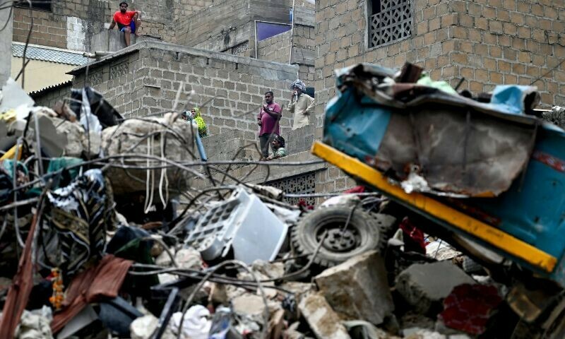 Residents look at the debris of a collapsed building, from their homes in Karachi on July 5, 2025. Rescue teams pulled more bodies from the rubble of a five-storey building collapse in Pakistan overnight, taking the toll on July 5 to 14 as the recovery operation continued for a second day. — AFP