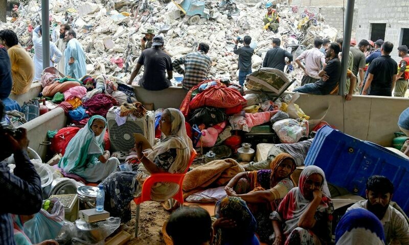 Families wait amidst the debris of a collapsed building in Karachi on July 5, 2025. Rescue teams pulled more bodies from the rubble of a five-storey building collapse in Pakistan overnight, taking the toll on July 5 to 14 as the recovery operation continued for a second day. — AFP