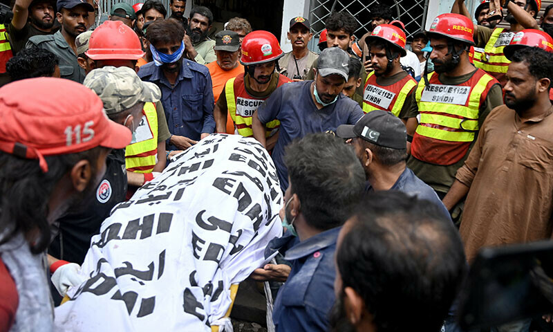Rescue workers recover a victim’s body during a search operation amid the debris of a collapsed residential building in Karachi on July 6. — AFP