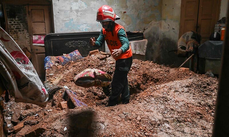 A rescue worker clears debris from a collapsed roof after heavy monsoon rains in Lahore on July 10, 2025. — AFP