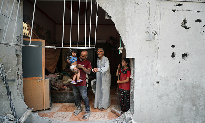 Palestinians stand at the site of an overnight Israeli air strike on a house, in Gaza City, on July 11. &mdash; Reuters