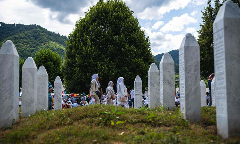Three women walk near gravestones at the memorial cemetery in the village of Potocari, near the eastern Bosnian town of Srebrenica, on July 11, on the 30th anniversary of the Srebrenica massacre. — AFP