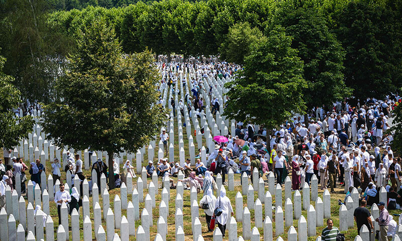 People gather among gravestones at the memorial cemetery in the village of Potocari, near the eastern Bosnian town of Srebrenica, on July 11,  on the 30th anniversary of the Srebrenica massacre. — AFP