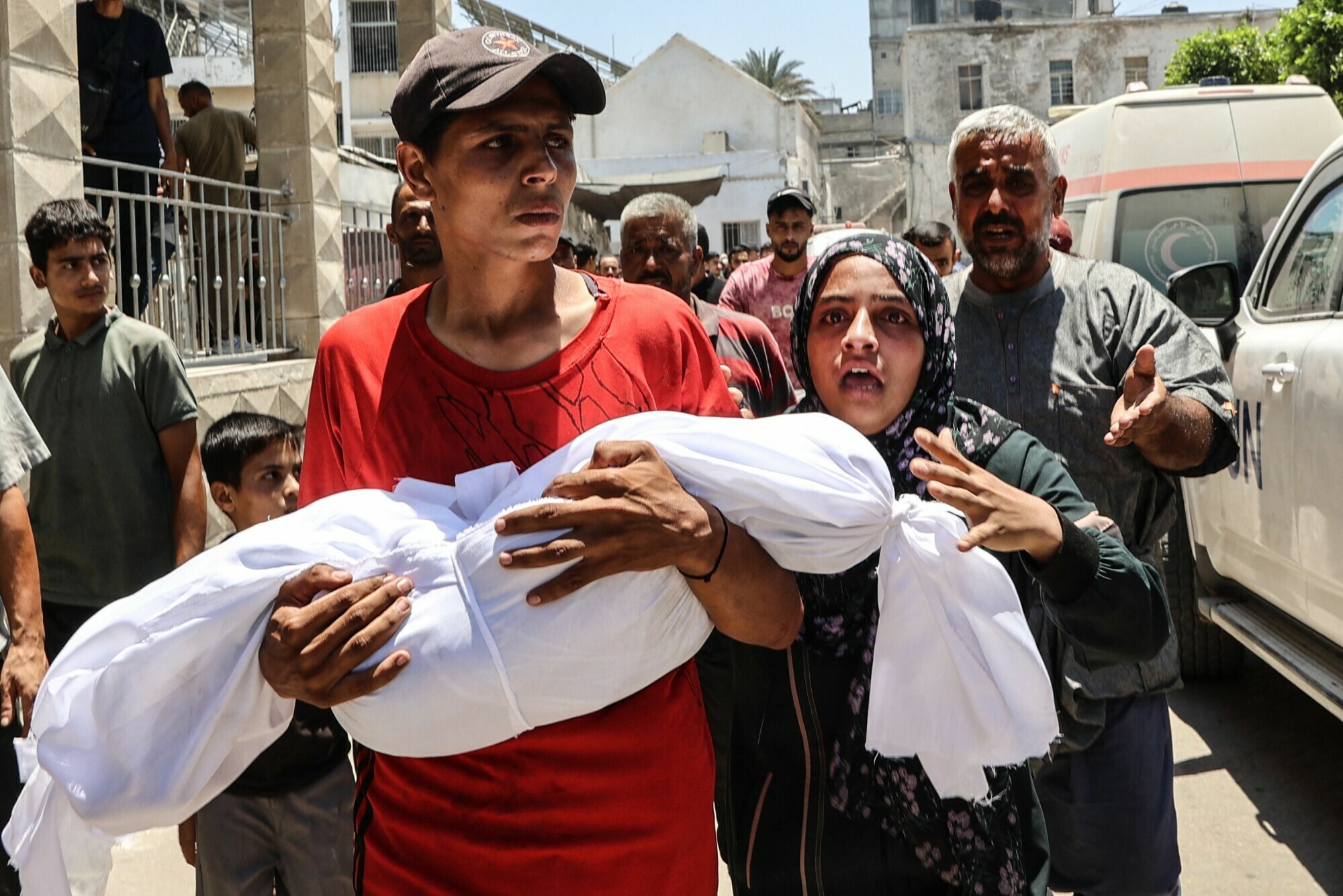 A Palestinian woman reacts as a young man carries the body of her child killed in an Israeli strike, in front of Gaza City’s Maamadani (Baptist) hospital on July 13. — AFP