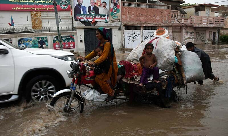 A family stuck in the rain in Hyderabad’s Latifabad area on July 14. — Umair Ali