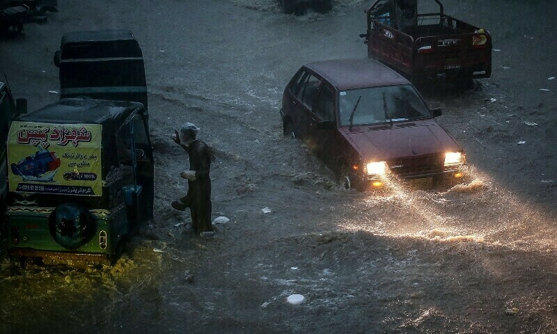 Commuters make their way through a flooded road during heavy monsoon rains in Hyderabad, Sindh province, on July 14. — AFP
