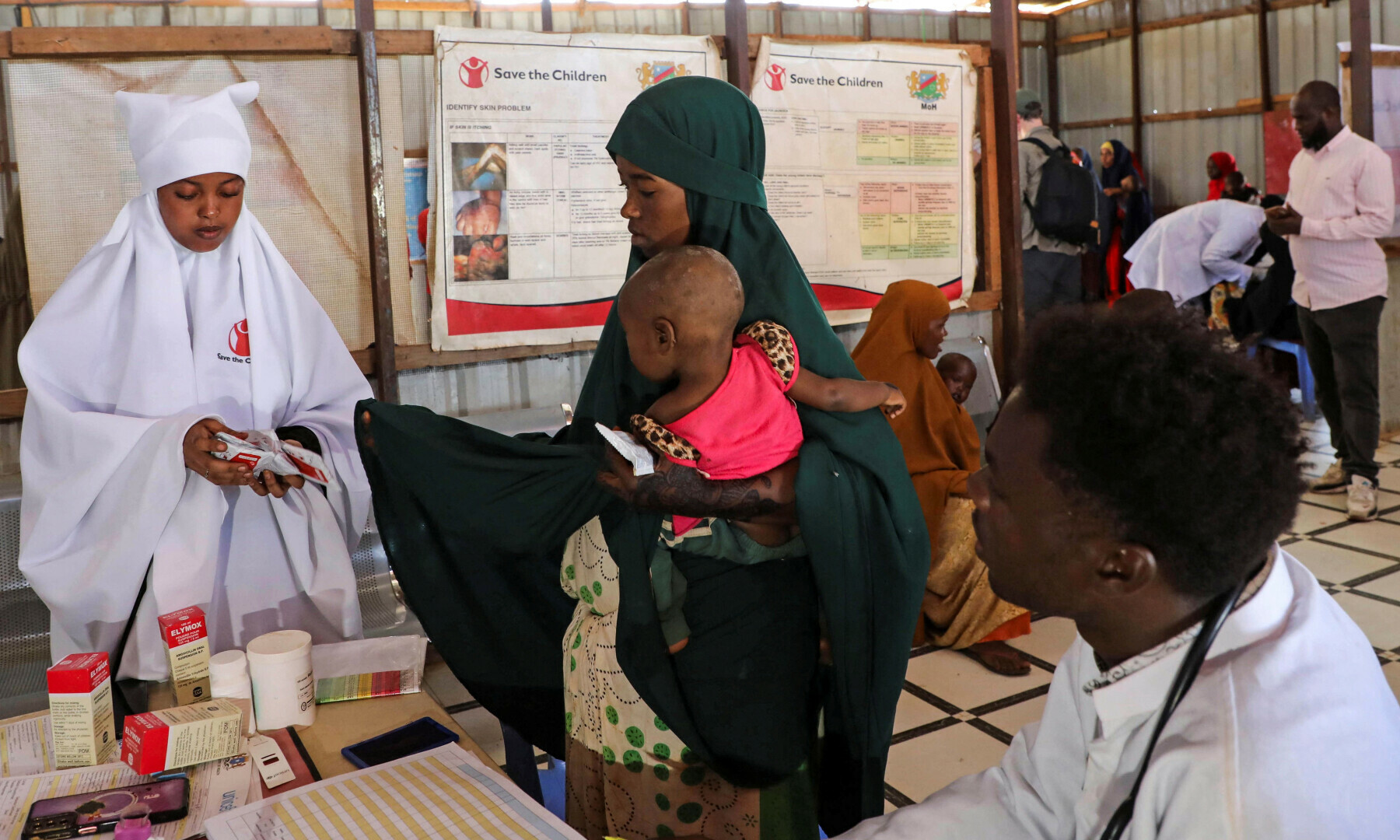 A nurse from Save the Children distributes Plumpy’nut, used to treat severe acute malnutrition in children, to an internally displaced Somali woman, at the Tawakal 2 camp in Baidoa, southwest Somalia on June 24, 2025. — Reuters/Feisal Omar