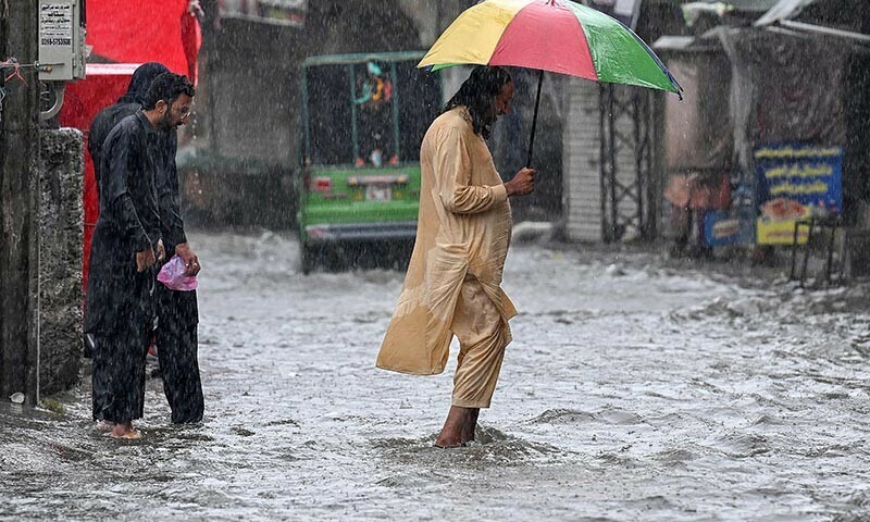 People wade through a flooded street during heavy monsoon rains in Rawalpindi on July 17, 2025.  — AFP
