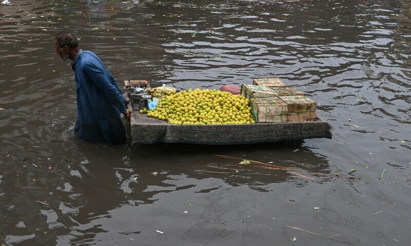 A vendor pulls his cart through flooded streets after heavy monsoon rains in Lahore on July 16. — AFP
