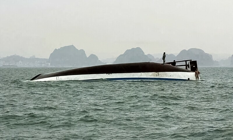 A man stands on a tourist boat that capsized in Ha Long Bay, Quang Ninh province on July 19. — AFP