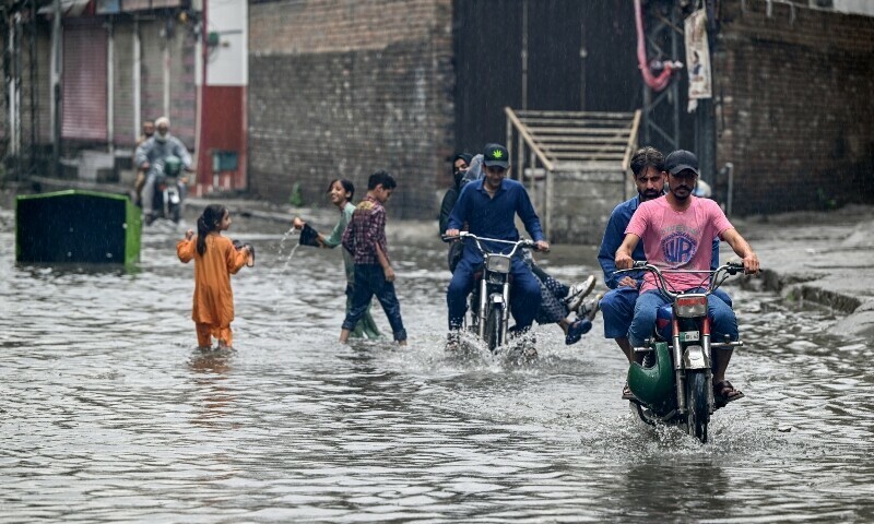 Commuters wade through a flooded street amidst heavy monsoon rains in Rawalpindi on July 17. &mdash; AFP