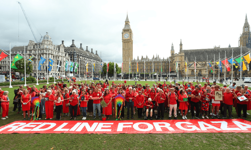 Members of the public gather in Parliament Square wearing red and holding items behind a giant &lsquo;Red Line for Gaza&rsquo; banner to symbolise what is being lost due to the conflict, in London, Britain, on July 22. &mdash; Reuters