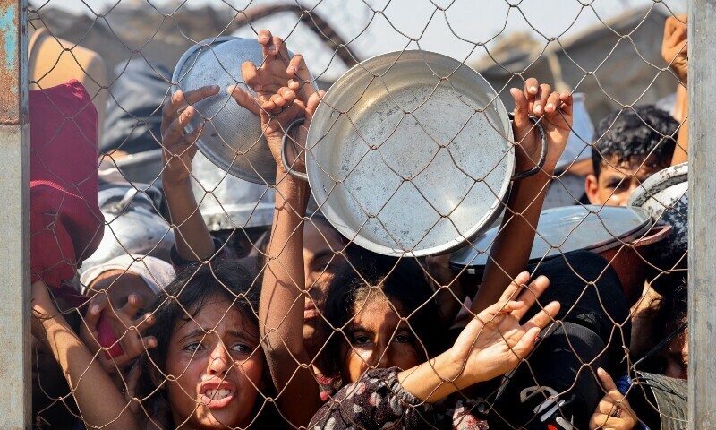 Palestinians, mostly children, push to receive a hot meal at a charity kitchen in the Mawasi area of Khan Yunis in the southern Gaza Strip on July 22. — AFP Palestinians, mostly children, push to receive a hot meal at a charity kitchen in the Mawasi area of Khan Yunis in the southern Gaza Strip on July 22. — AFP