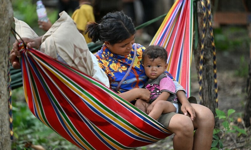 A woman and her baby who fled their home near the Cambodia-Thailand border rest on a hammock on the grounds of a pagoda in Oddar Meanchey province on July 25. — AFP