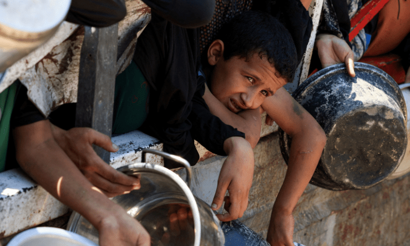  A boy looks on as Palestinians gather to receive food from a charity kitchen, amid a hunger crisis, in Gaza City, July 25. &mdash; Reuters 