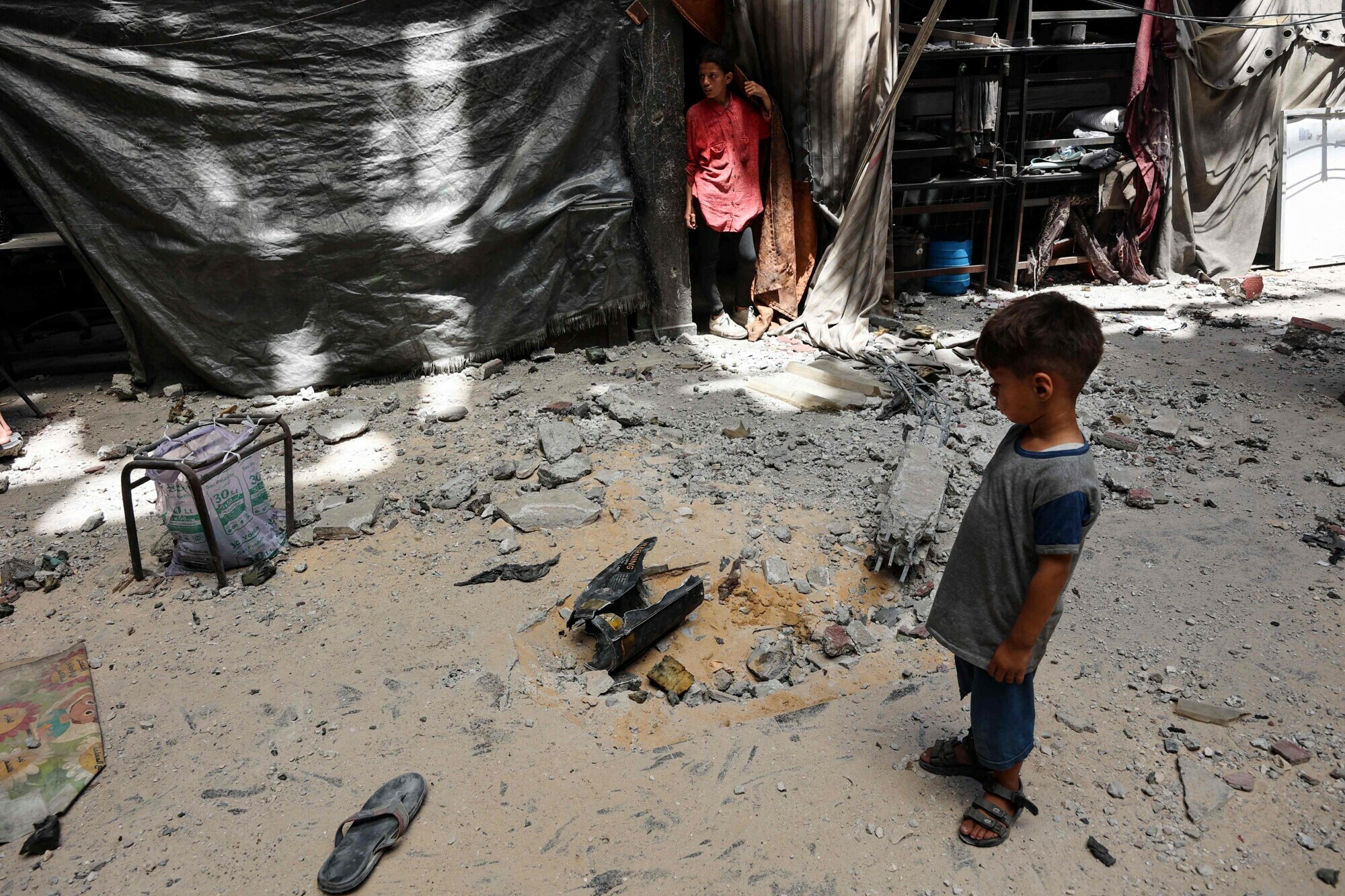Palestinian children stand at the site of an Israeli strike on a school sheltering displaced people, in Gaza City, July 25. &mdash; Reuters