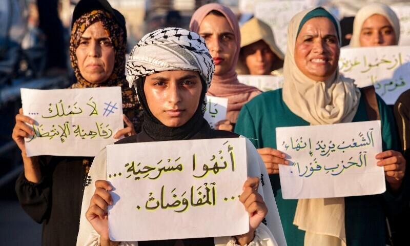 Women and children hold up signs as they attend a silent march against war and hunger in the Mawasi area in the east of Khan Yunis in the southern Gaza Strip on July 26. &mdash; AFP