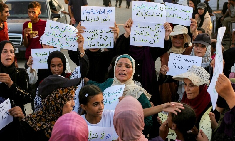 Women and children hold up signs as they attend a silent march against war and hunger in the Mawasi area in the east of Khan Yunis in the southern Gaza Strip on July 26. &mdash; AFP