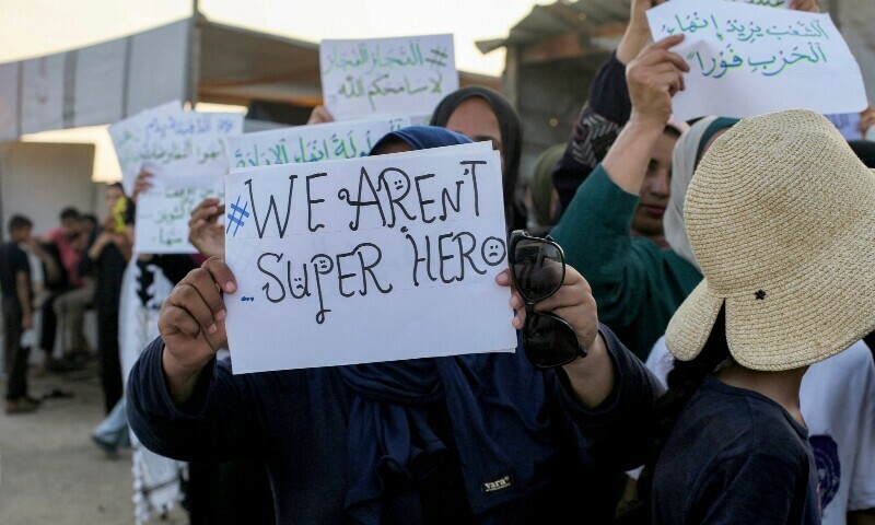 Women and children hold up signs as they attend a silent march against war and hunger in the Mawasi area in the east of Khan Yunis in the southern Gaza Strip on July 26. &mdash; AFP
