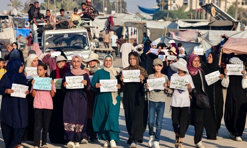 Women and children hold up signs as they attend a silent march against war and hunger in the Mawasi area in the east of Khan Yunis in the southern Gaza Strip on July 26. &mdash; AFP