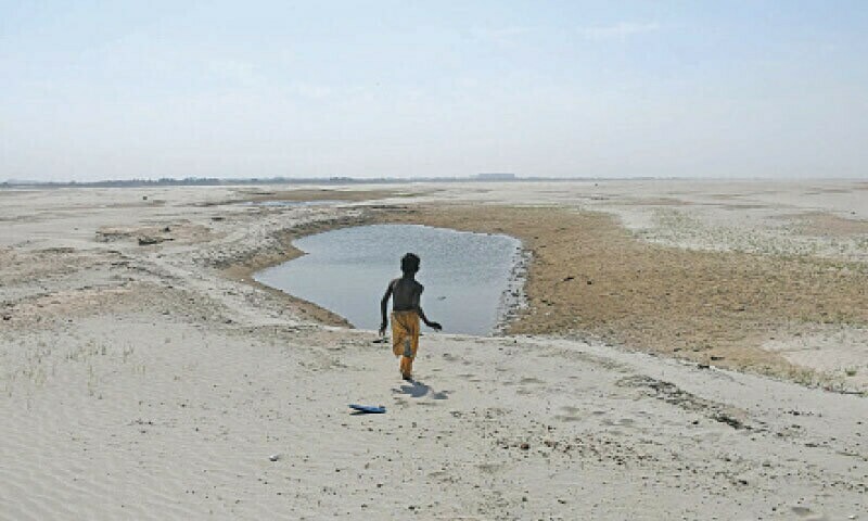 HYDERABAD: A child runs through the dry bed of the River Indus, downstream of Kotri barrage.—Umair Ali